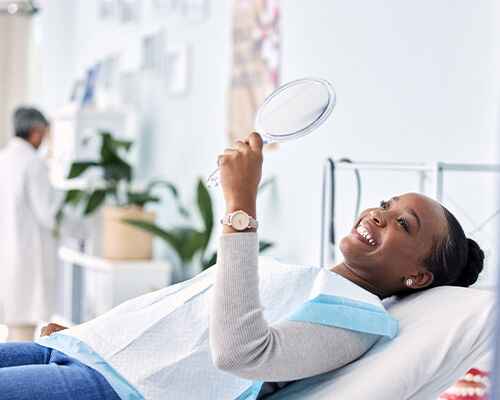 Woman smiling at reflection in handheld mirror