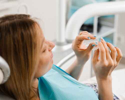 Patient holding clear aligner in treatment chair