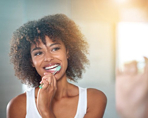 A Cheerful woman brushing her teeth in a bathroom