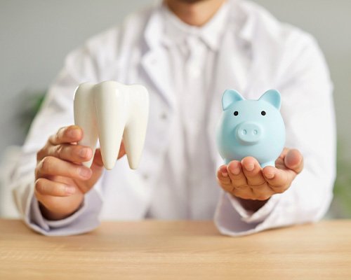 a dentist holding a model tooth and a piggy bank