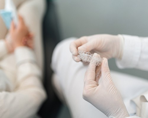 A dentist showing an Invisalign tray to her patient