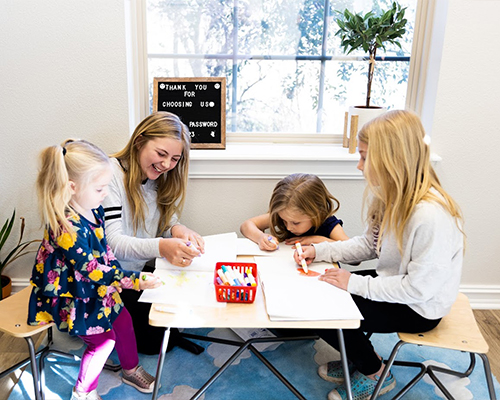 Mother and three daughters coloring with markers in Jenks dental office