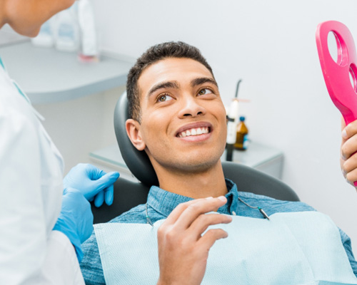 Patient smiling at dentist with pink mirror