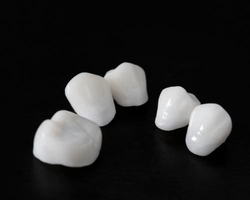 Five metal free dental crowns against a black background