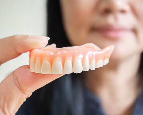 woman holding a full denture