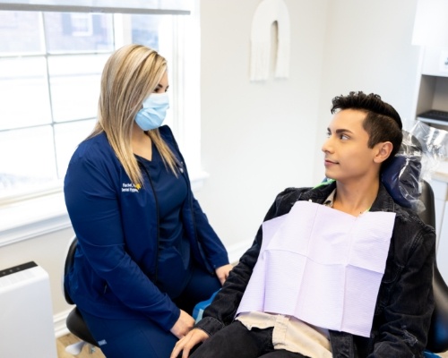 Man in dental chair talking to a dental team member