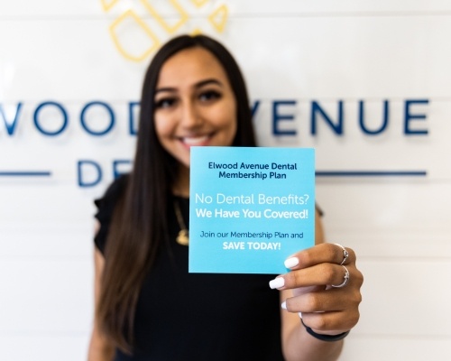 Dental team member holding a card that says Elwood Avenue Dental Membership Plan