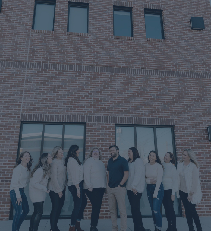 Jenks dentists and dental team members standing in a line in front of brick building