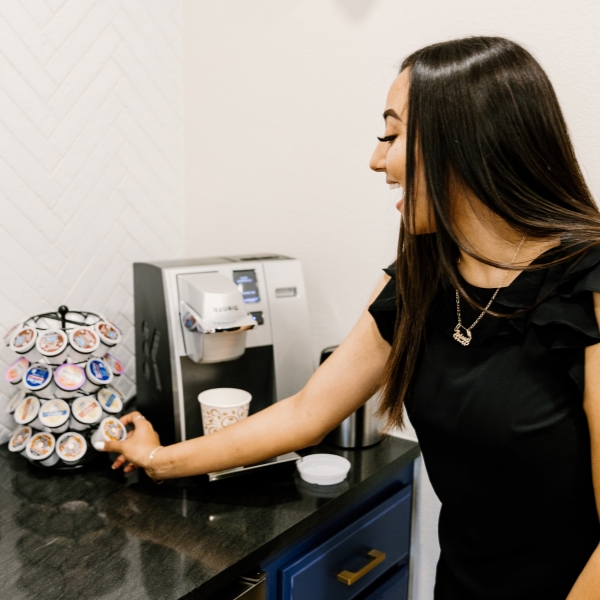 Jenks dental team member stocking K cups next to coffee machine