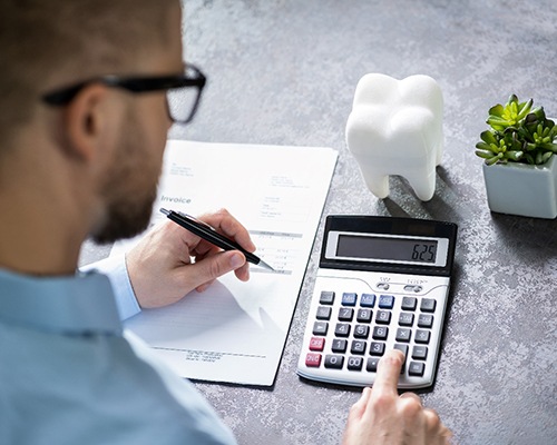 Man using calculator to determine cost of dentistry