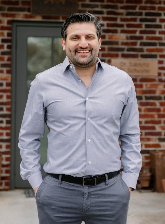 Doctor Salayta smiling while standing in front of brick wall