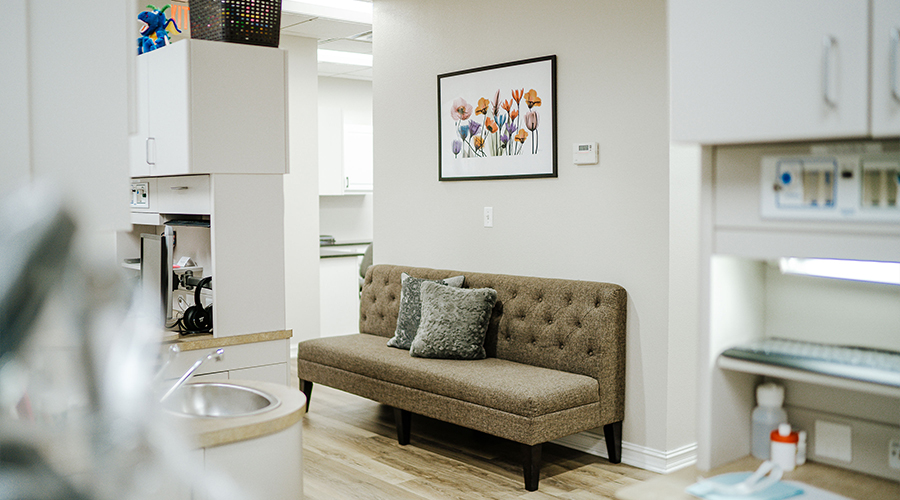 Light green couch with flower painting on wall above it in dental office