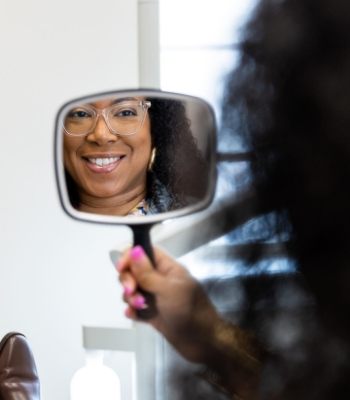 Dental patient with glasses seeing her smile in a mirror