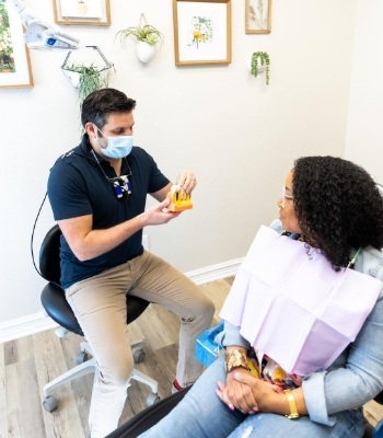 Doctor Salayta showing a patient a model of a dental implant