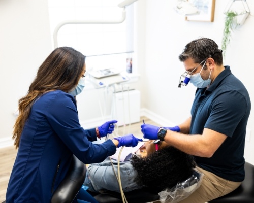 Dentist and team member giving a patient a teeth cleaning in Jenks