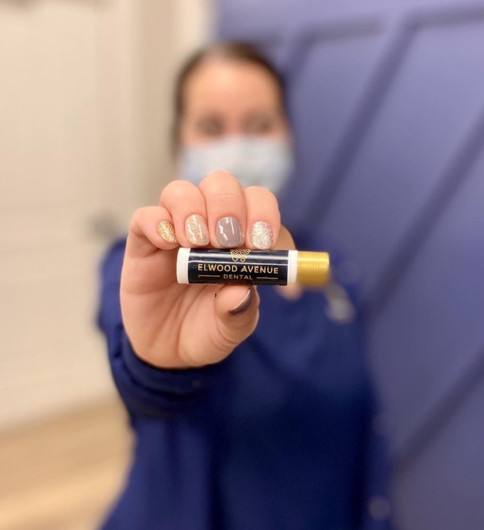 Dental team member holding chapstick that says Elwood Avenue Dental