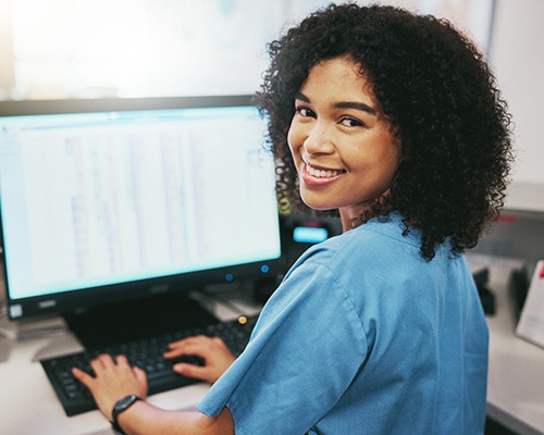a dental assistant working at a computer and smiling