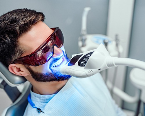 Man in dental chair with ultraviolet light applied to teeth whitening