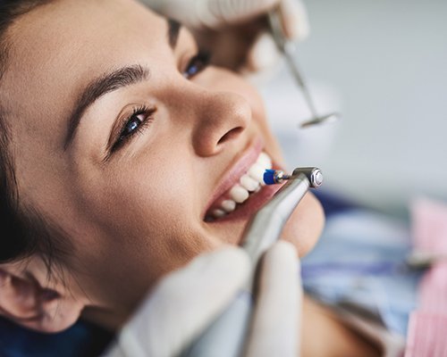 Closeup of hygienist’s hands polishing a woman’s teeth