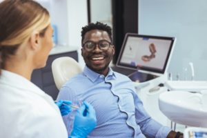 A man in a dentist's chair smiling at his dentist next to him