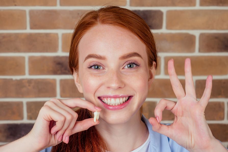 A woman holding an extracted tooth.