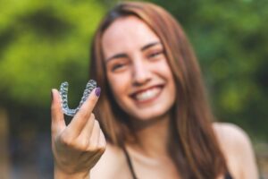 Woman holding Invisalign clear aligner. 
