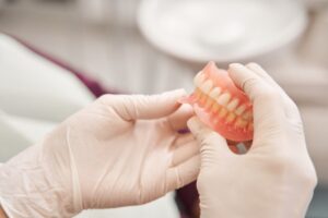 Gloved hands holding set of dentures. 