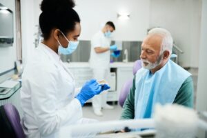 Dentist holding denture while patient looks on. 